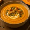 Soupe de potimarron crémeuse servie dans un bol en céramique avec croûtons et graines de courge