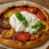 Tarte à la tomate au Thermomix garnie de tomates colorées, oignons caramélisés et burrata crémeuse, décorée de basilic frais.