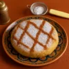 pastilla de poulet marocaine dorée sur assiette traditionnelle, saupoudrée de sucre glace et de cannelle